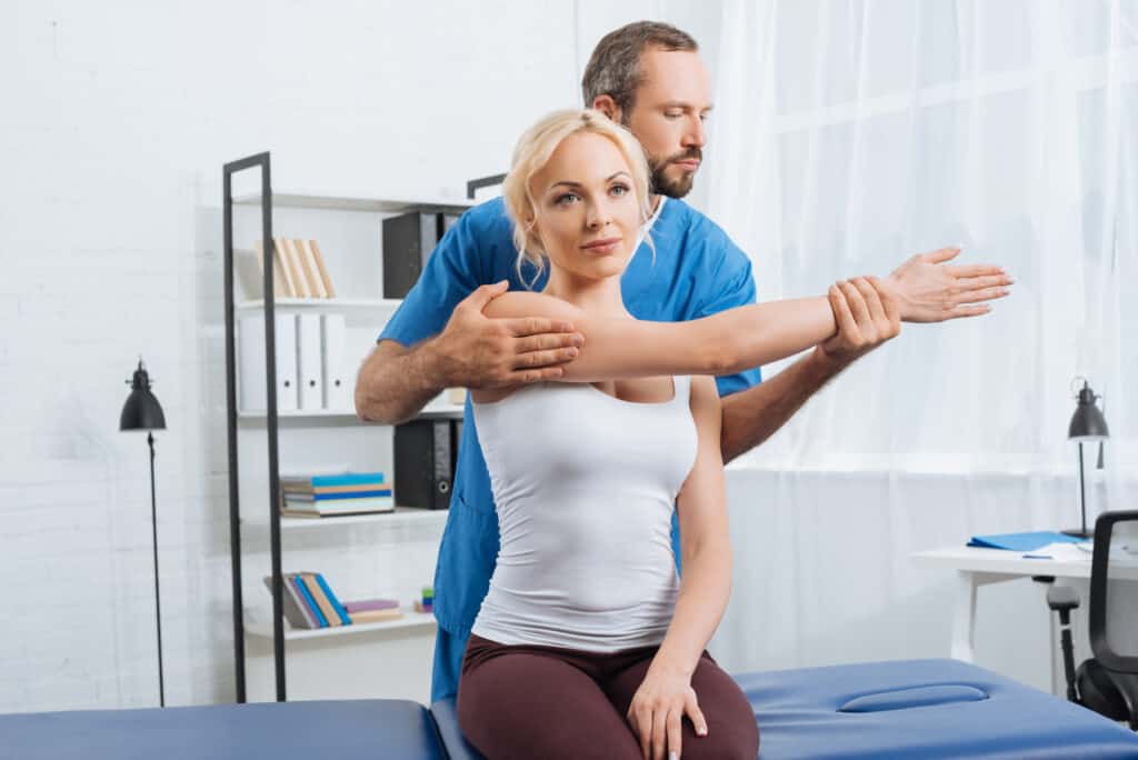 male physical therapist helping with woman who has shoulder pain 