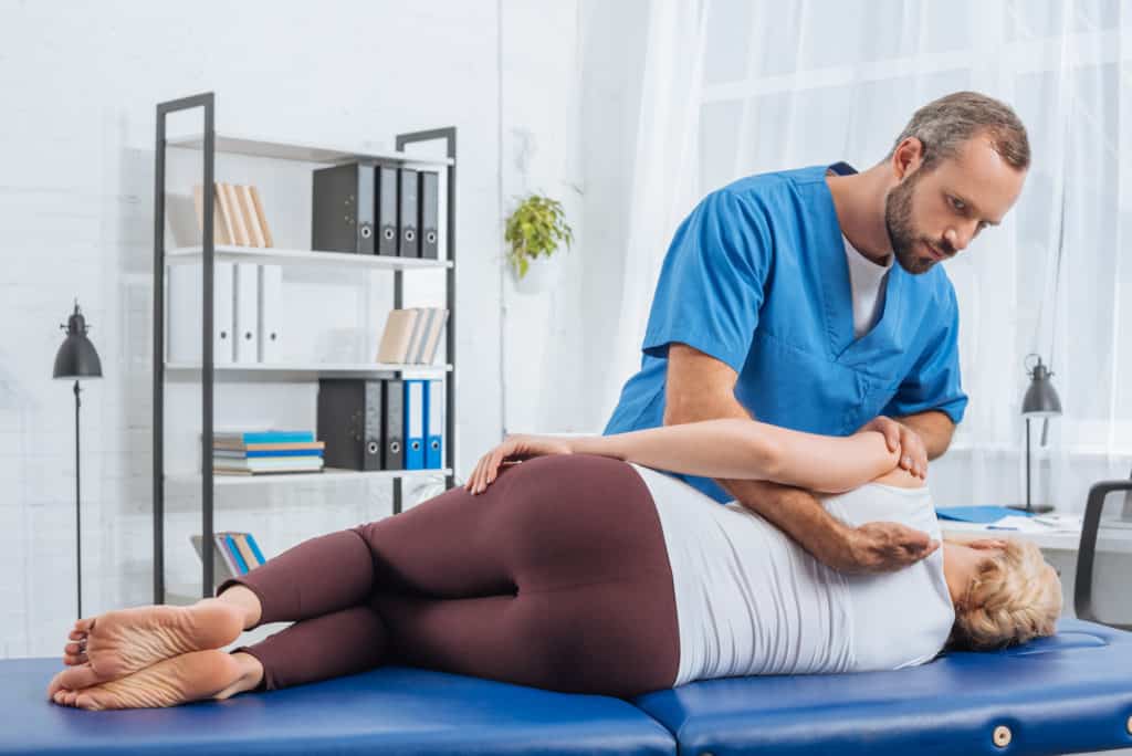 physical therapist helping patient's back