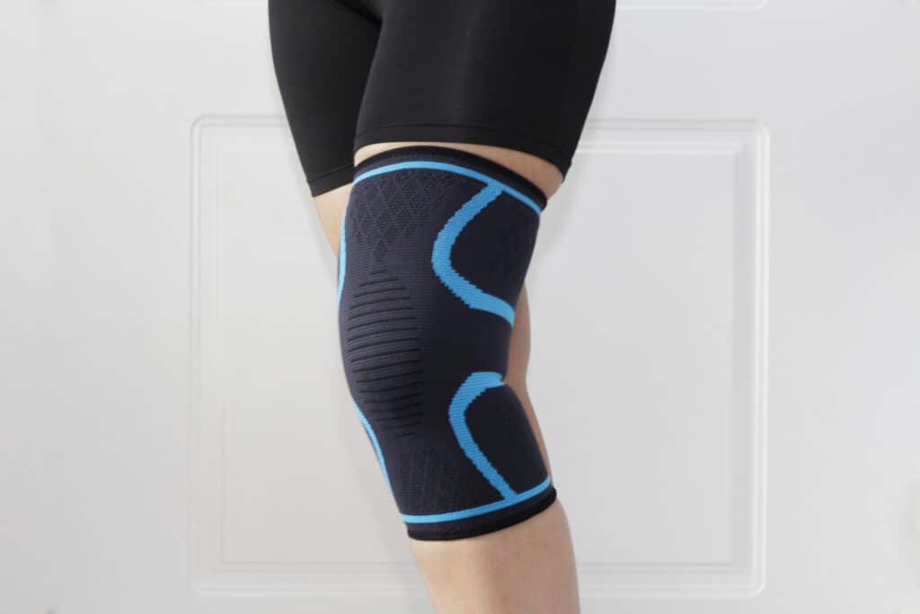Closeup of a leg with one grip of a knee brace. Orthopedic knee pad. A woman wears a knee brace. Knee joint problem.