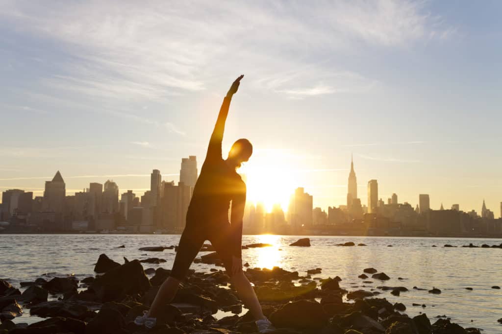 Early morning Woman Runner Yoga Stretching Manhattan Skyline Sunrise New York