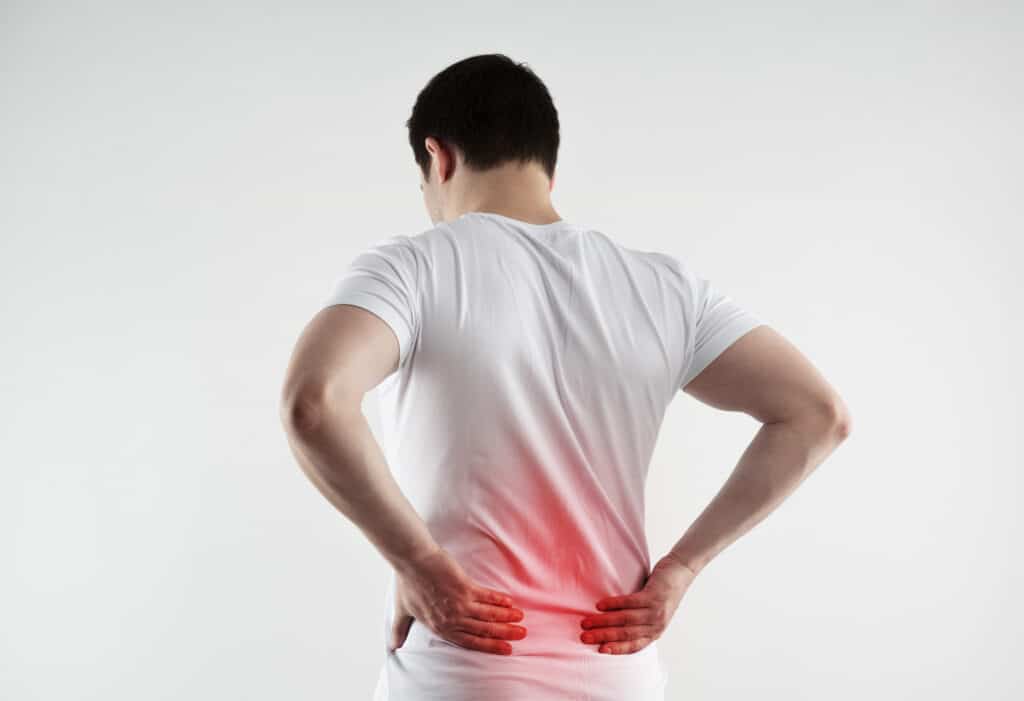 why am i experiencing prolonged coccyx pain - man holding lower part of back in pain